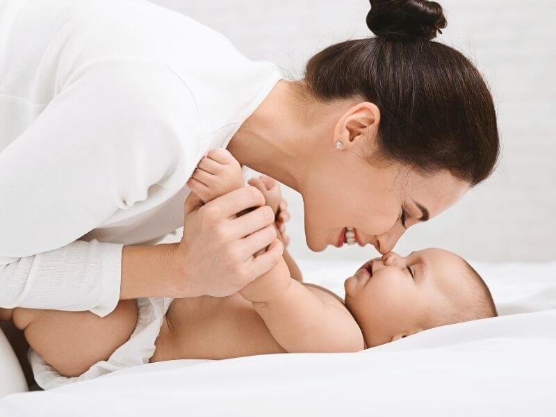 Madre jugando con su bebé recién nacido, imagen para la sección sobre contratar un seguro después del nacimiento del bebé.